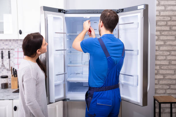 Woman Looking At Male Repairman Fixing Refrigerator With Screwdriver dfs 7